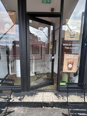 Glass door with black metal frames ahead. Push handle on right to open.