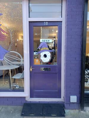 Glass door with wooden purple frame ahead. Push from handle on left to open.