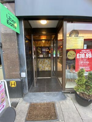 Archway followed by Brown framed glass door. Pull brown metal handle from right to open.
