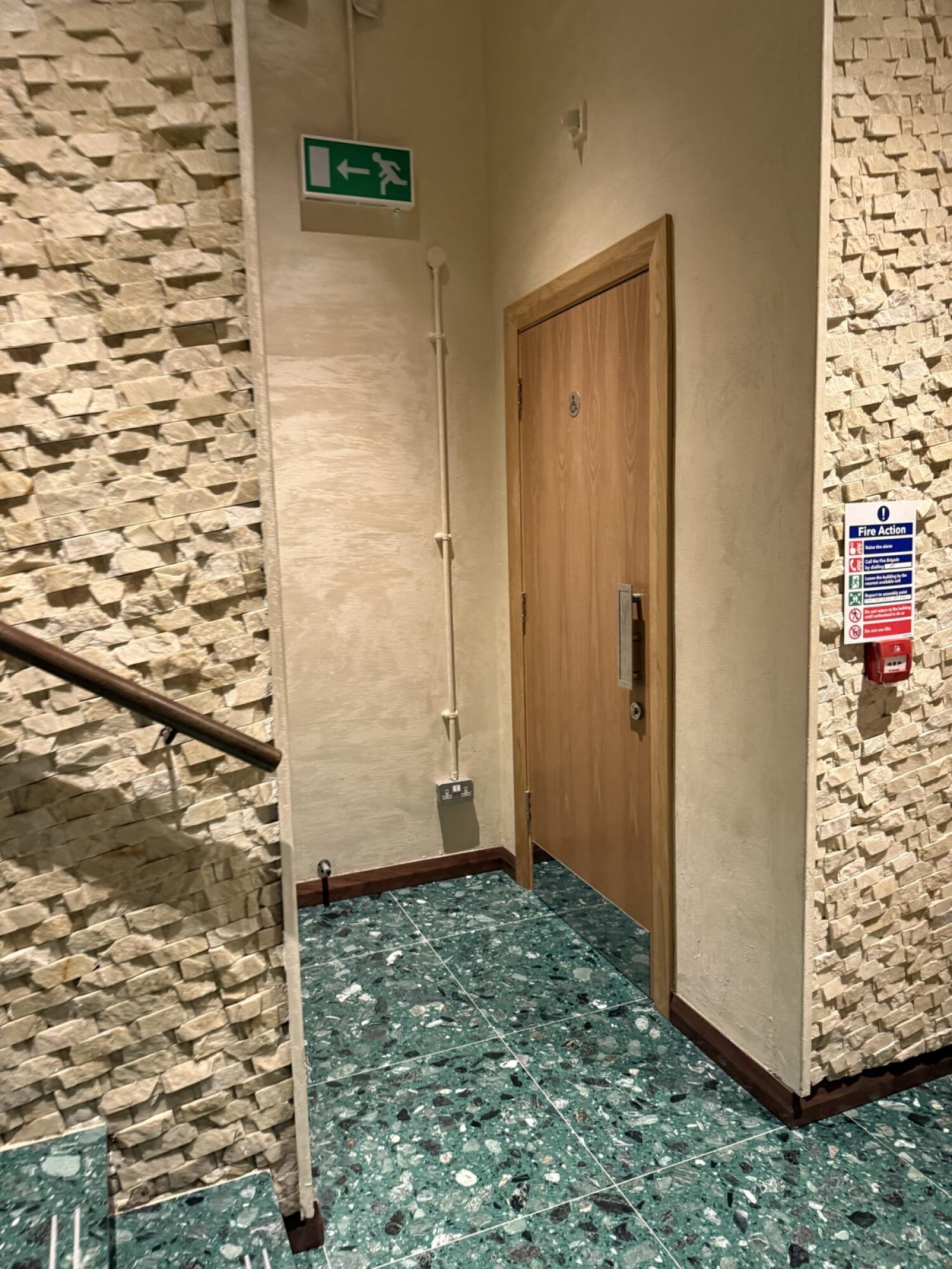 Staircase along left, leading up. Handrail along left. Door ahead on right.