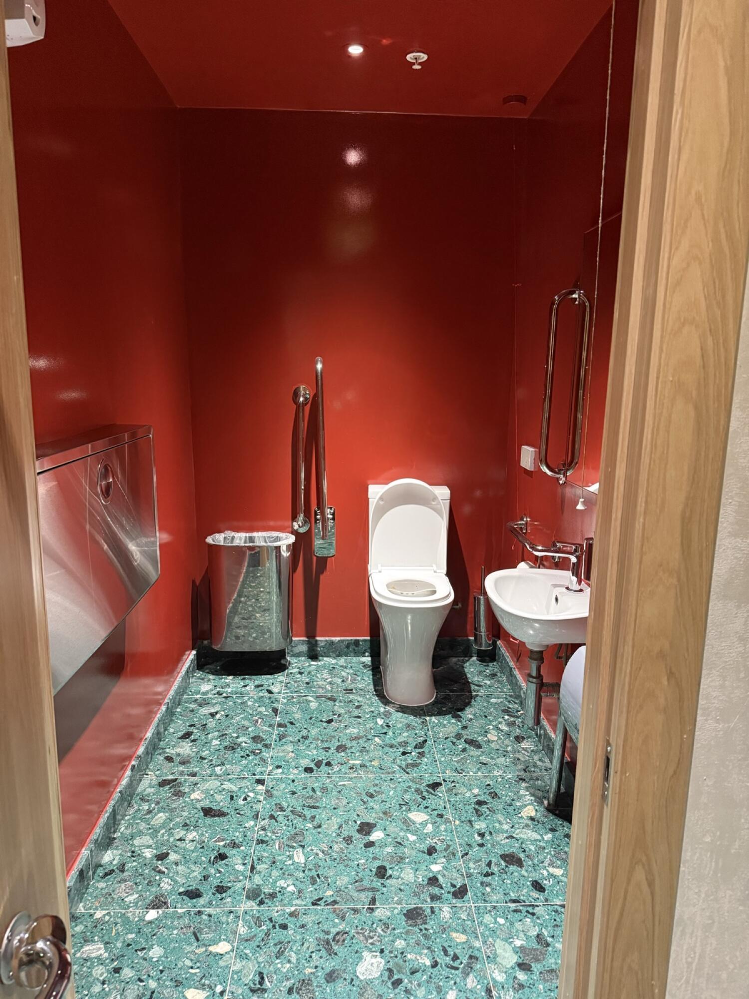 Baby changing station left. Toilet at back wall. Sink on right wall.