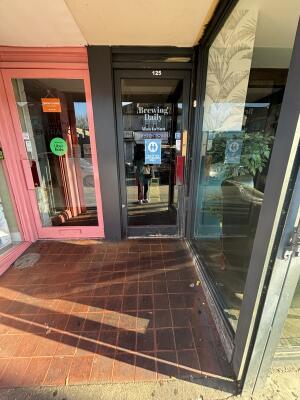 Black framed glass door ahead. Push from right to open inwards.