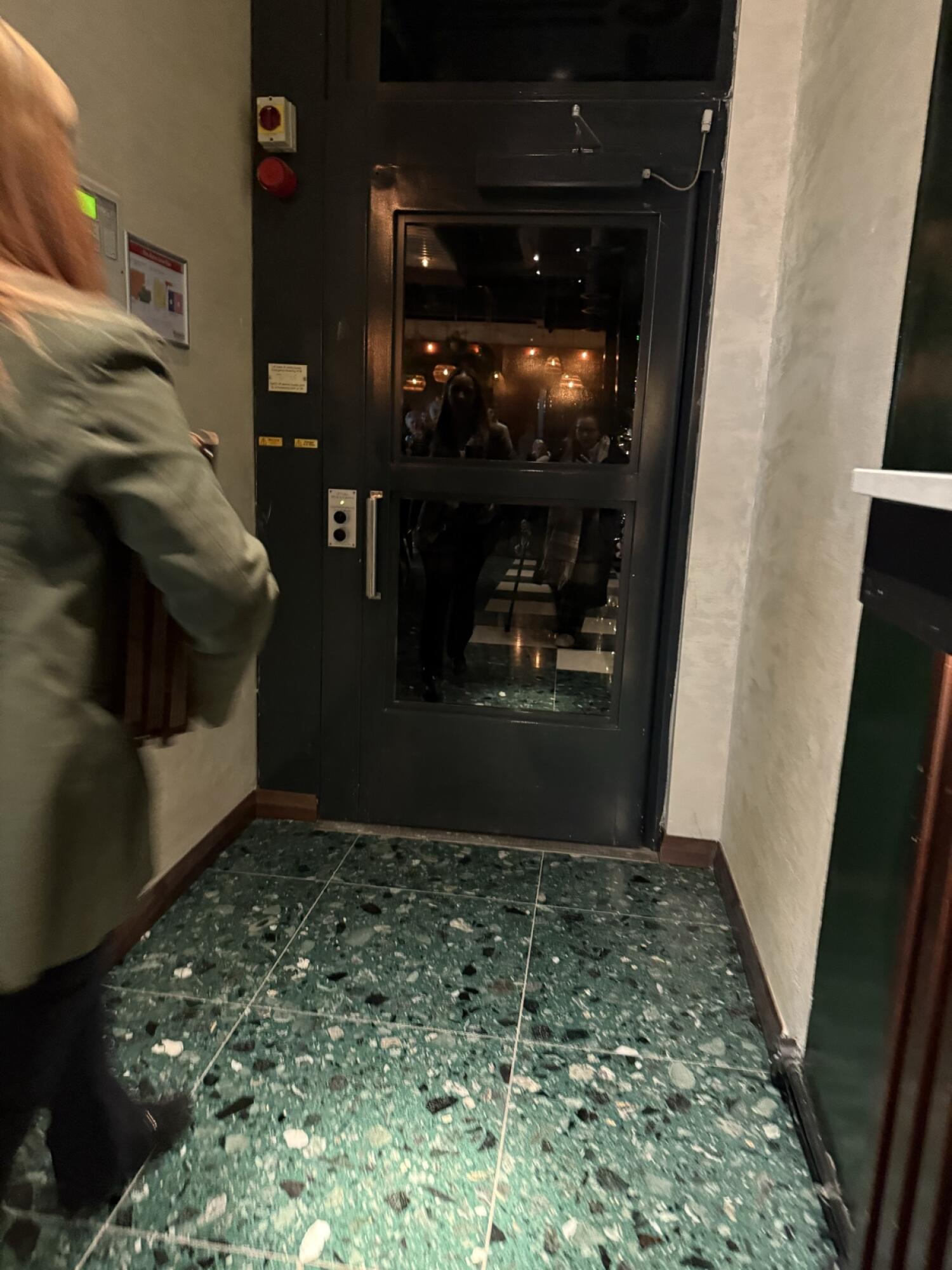 Dark metal-framed glass door ahead. Pull from handle on left to open.