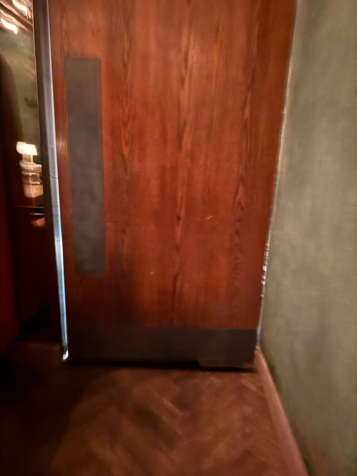 Brown wooden door. Pull from vertical handle on left to open.