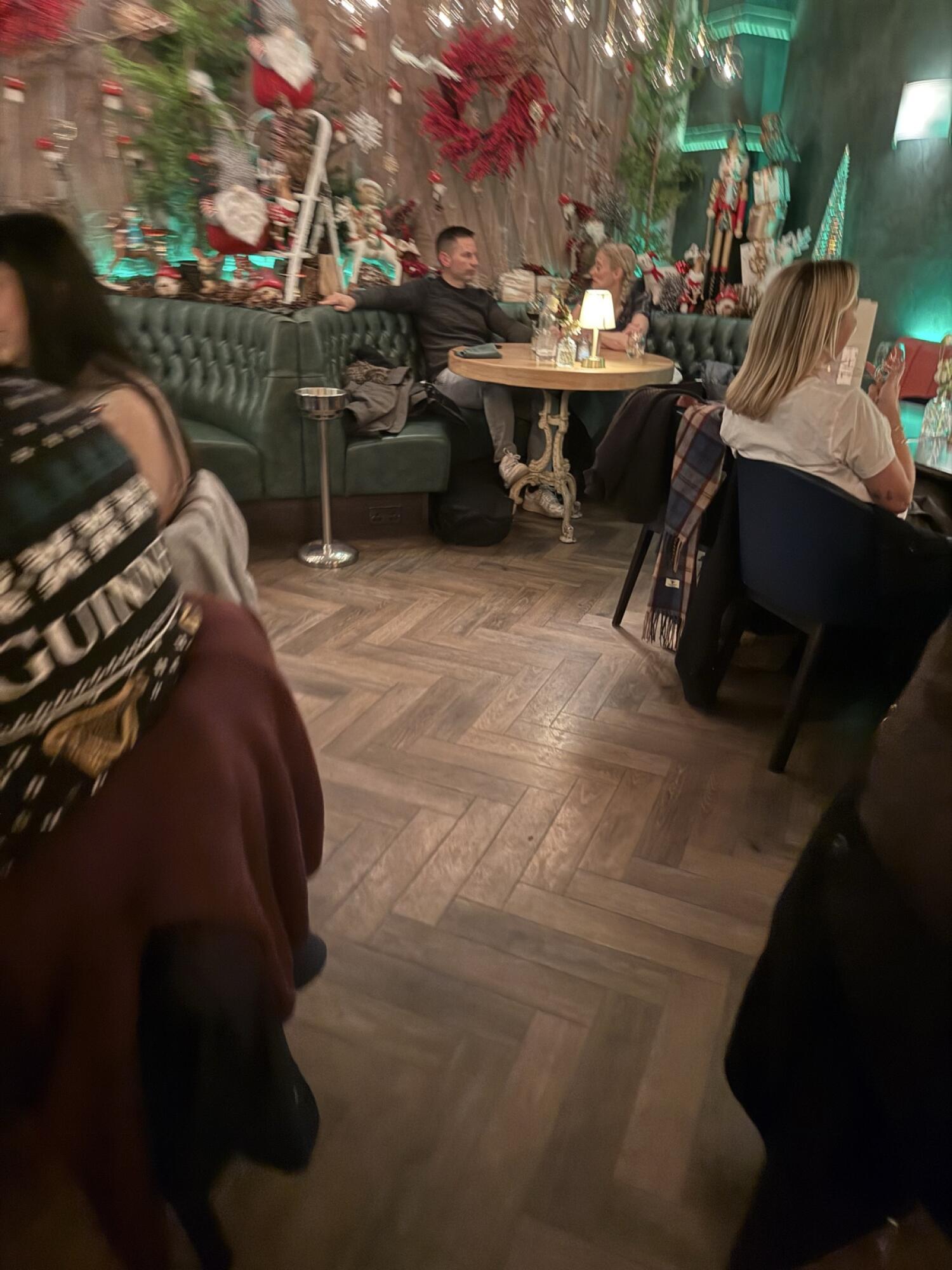 Half booth along back wall. Round table in centre. Chairs along right.