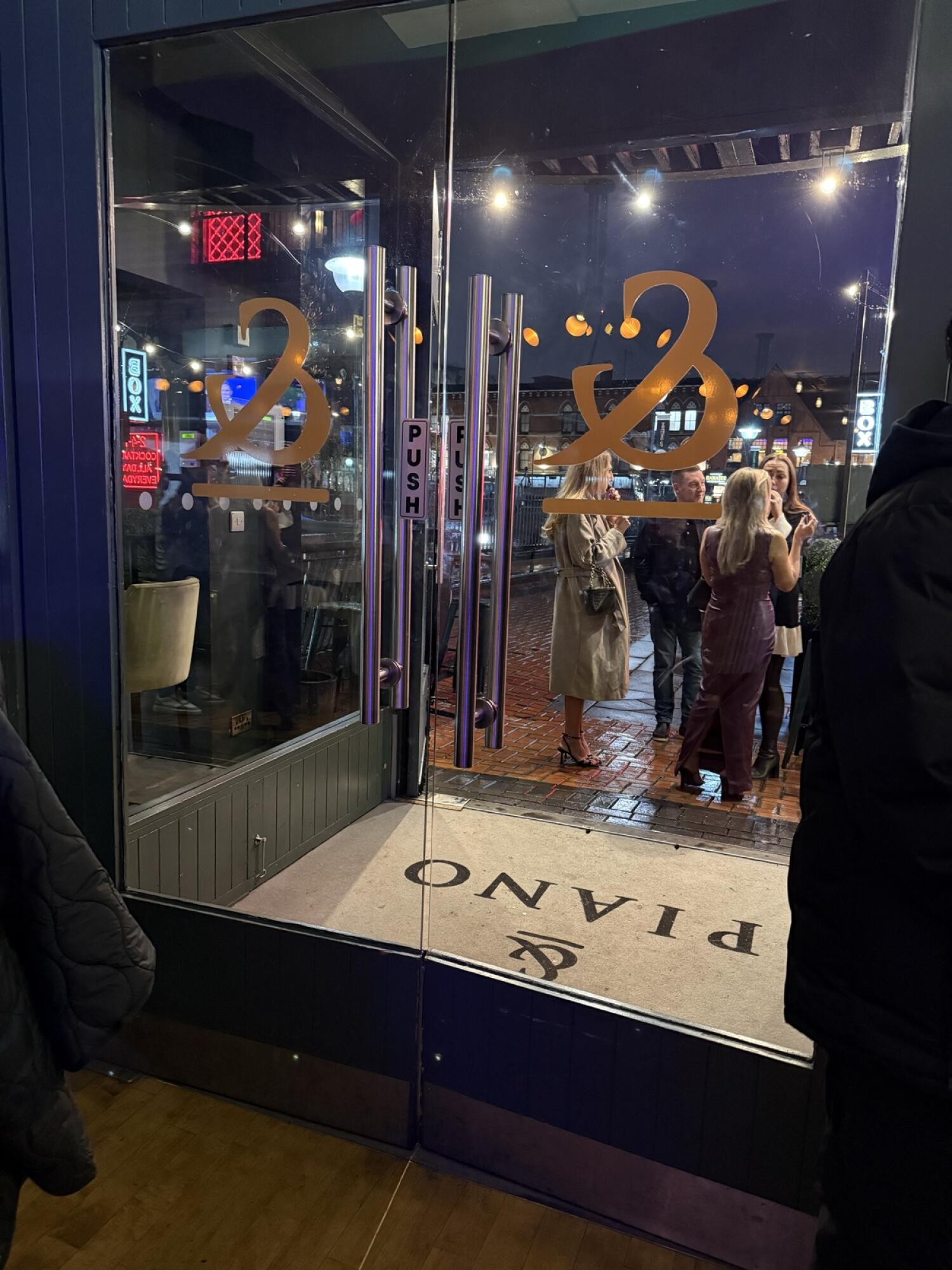 Glass doors with metal frame. Push from metal handles at centre to open.