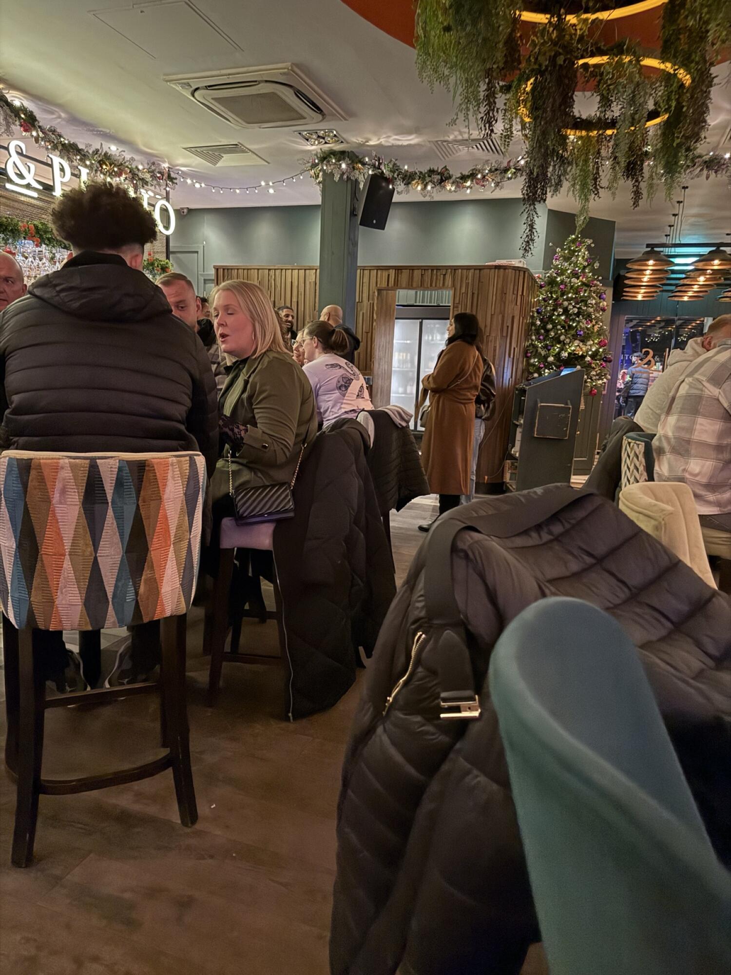 High chairs with patterned backs along left. Path in centre leading to fridge at back. Christmas tree to right of path.