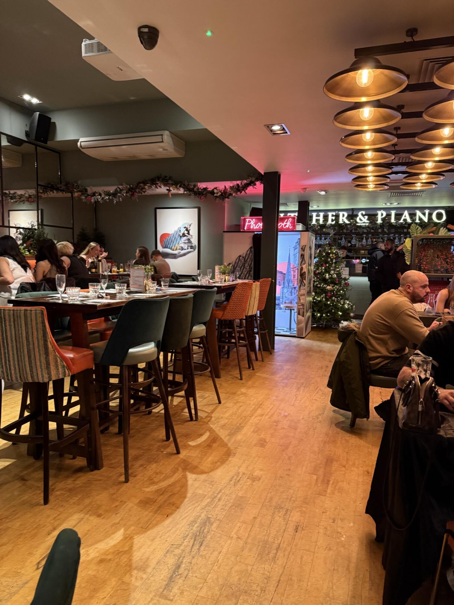 Tables and chairs along right. Path to bar in centre. High tables with stools along left.
