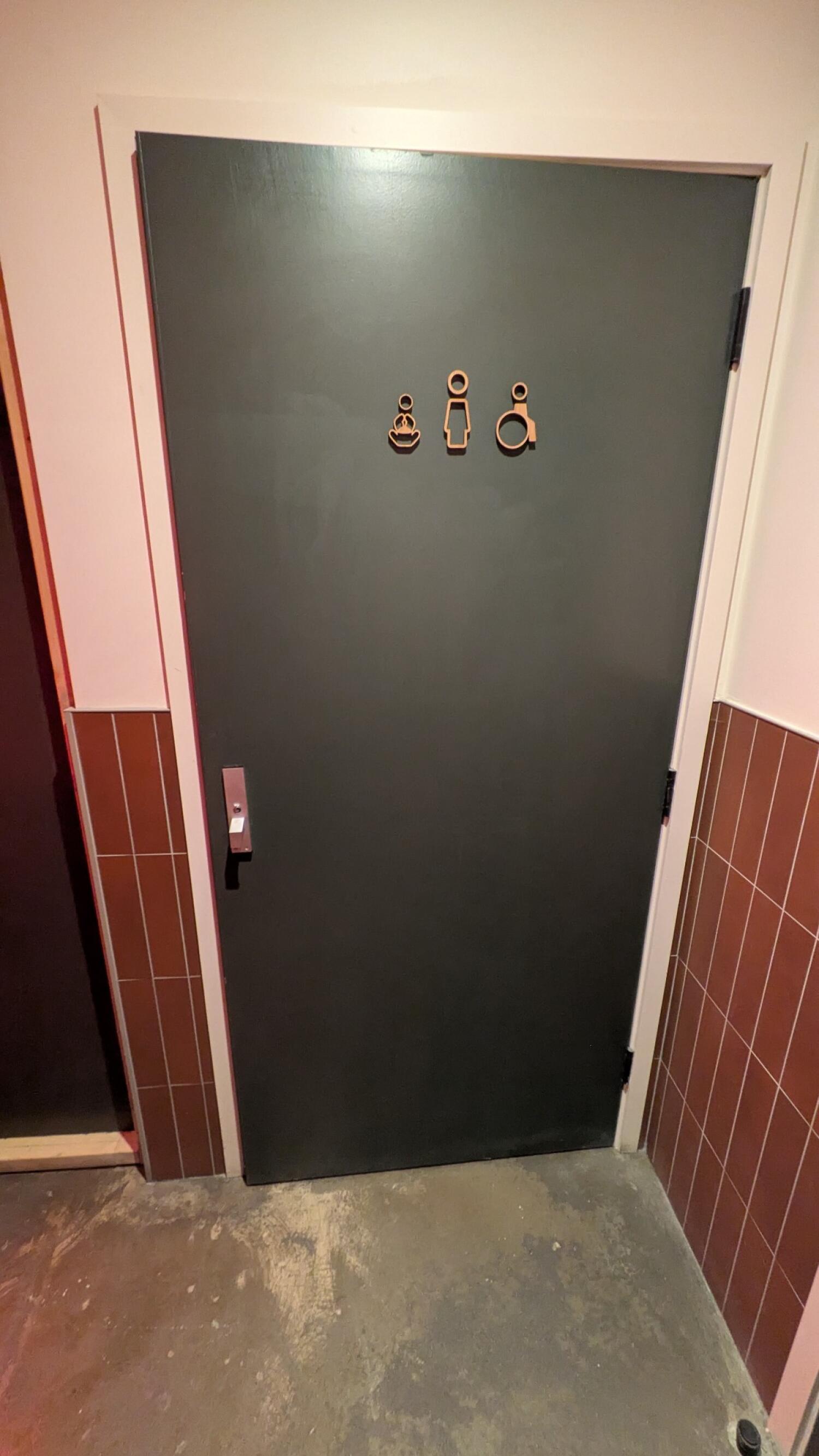 From end of path facing left. Dark grey door with white frame. Pull from metal handle on left to open.