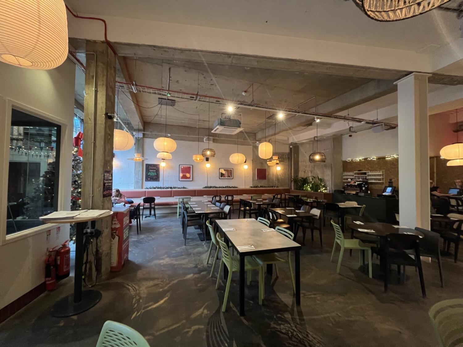 From entrance facing left. Half booth along back wall. Path in centre. Tables and chairs along left and right.