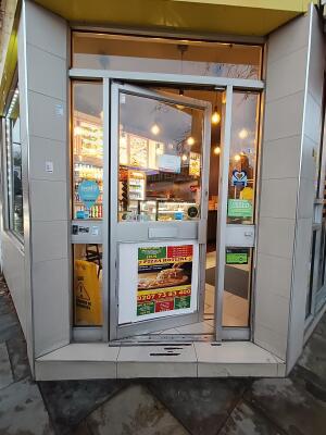 Silver metal-framed glass door. Push from handle on right to open.