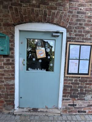 Light blue wooden door with glass panel. Pull from handle on left to open.