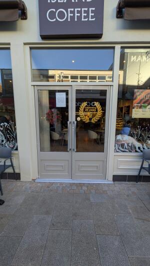 Light grey wood-framed glass doors. Pull from handles at centre to open.