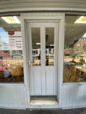 White wooden door with glass panelling. Turn and push silver metal handle from left to open.