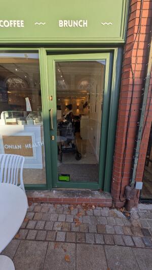 Green metal-framed glass door. Push from handle on left to open.