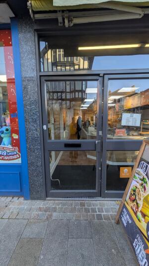 Dark metal-framed glass door. Push from handle on right to open.