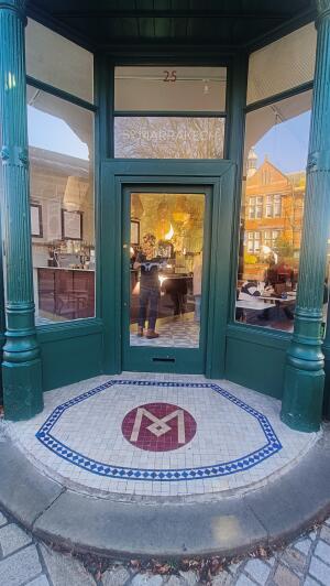 Green framed glass door to venue. Push on left to open.