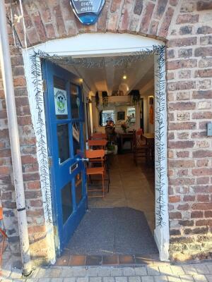 Glass door with blue frame ahead. Push from handle on right to open.