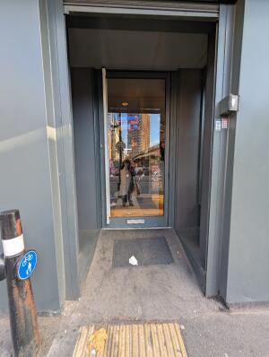Grey frame archway in front. Grey frame glass door at back. Silver handle on left. Push to open.