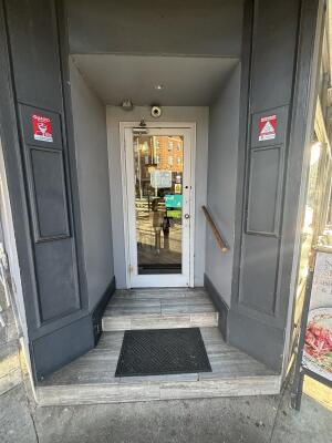 Archway ahead leading to white framed glass door at back. Pull handle on right to open. Handrail on right.