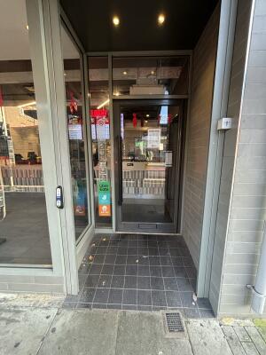 Archway ahead to black framed glass door at back. Pull handle on left to open.