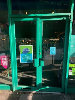 Green framed double glass door ahead. Push green handle in centre to open.