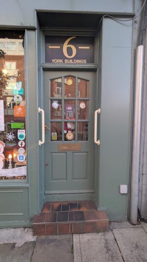 Green wooden door with glass panels. Push from handle on left to open. Grab rails on both sides.