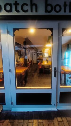 From right of entrance facing straight. White framed glass door ahead. Push handle on right to open.