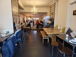From entrance facing straight. Tables and chairs along left and right. Path to back at centre.
