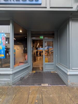 Grey frame opening in front. Grey frame glass doors at back. Gold metal pad in center. Push to open.