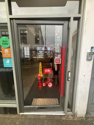 Grey framed glass door ahead. Push red handle on right to open.