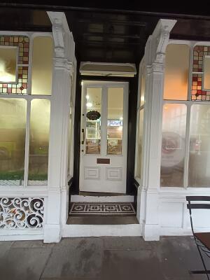 White wooden door with glass panel. Push from handle on left to open.