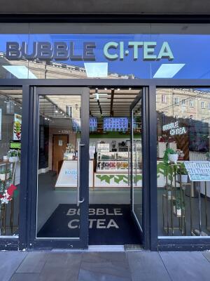 Glass doors with grey metal frames ahead. Push metal handle in center to open.