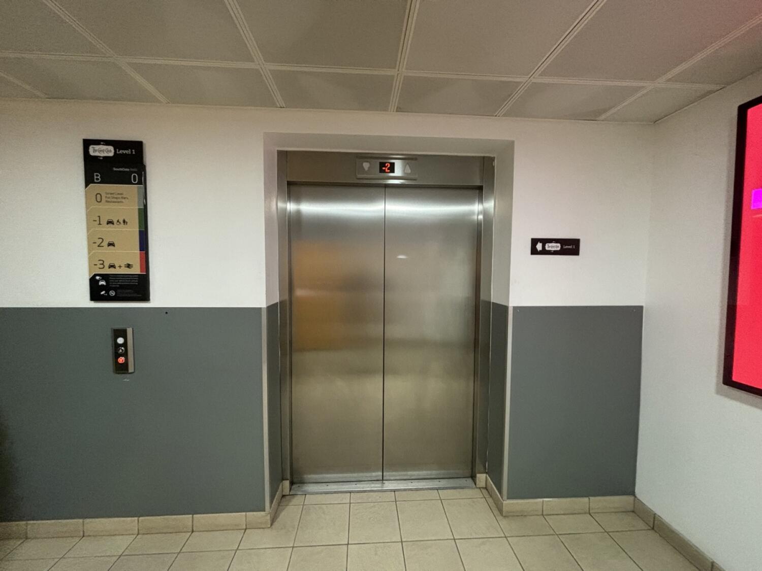 From door facing right. Lift ahead. Call buttons on left of lift.