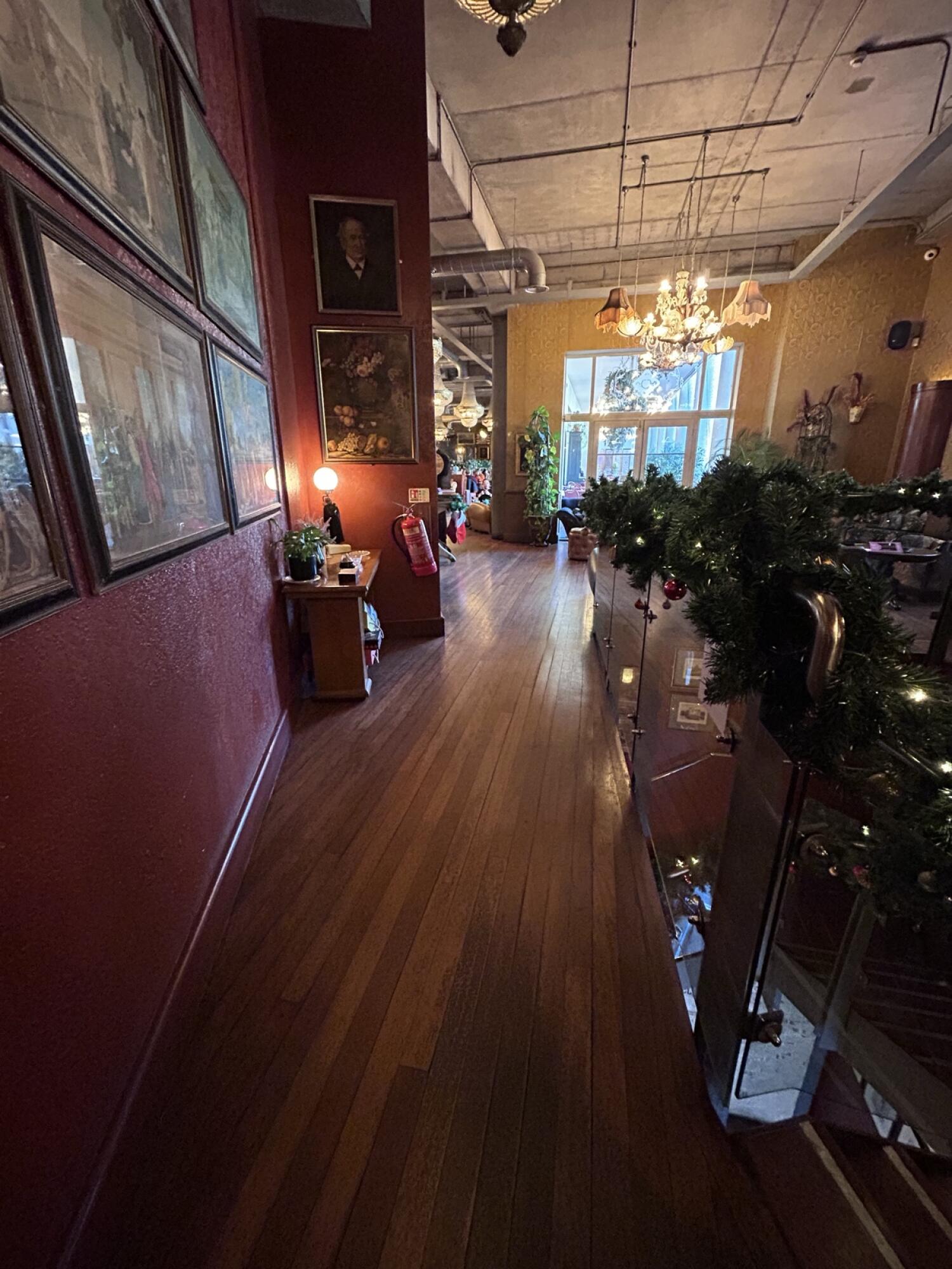 From top of stairs facing right. Table on left. Wall partition behind. Stair fence on right. Main space behind.