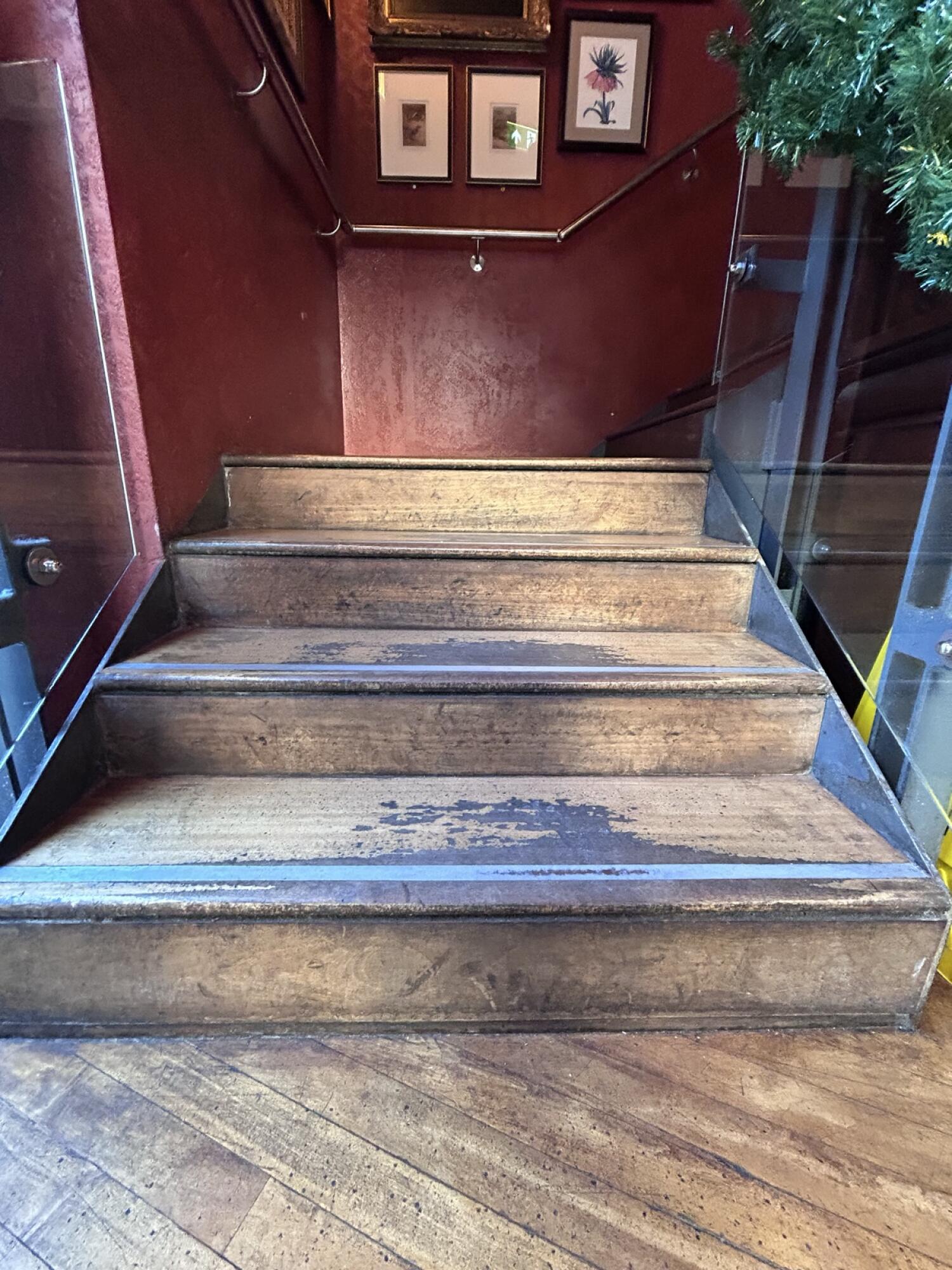 Wooden stairs with glass hand-rails going up.