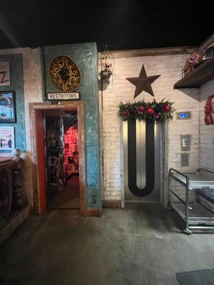 From left back of counter facing straight. Open archway to restrooms on left. Lift doors to bathroom on right.