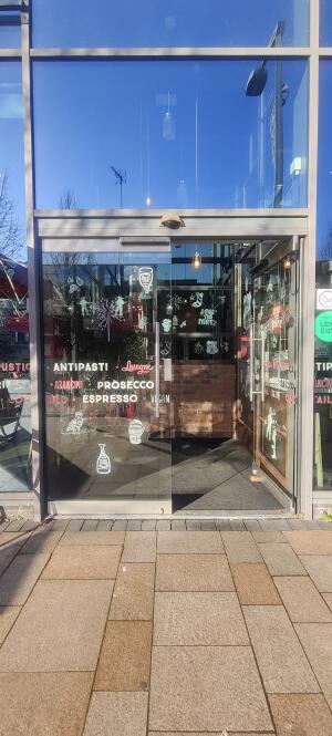 From street facing venue. Glass doors ahead. Push metal handle on center to open.