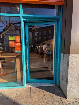 Blue frame glass door in front. Silver handle on left. Push to open.