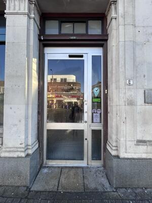 Glass door with grey metal frames ahead. Push from right to open.