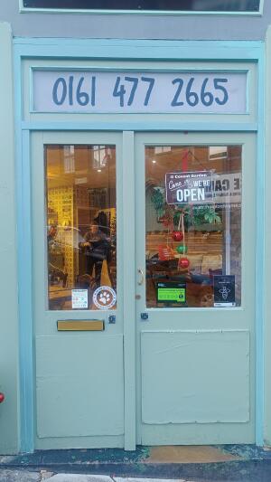 Green framed glass door to venue. Push handle in left to open.