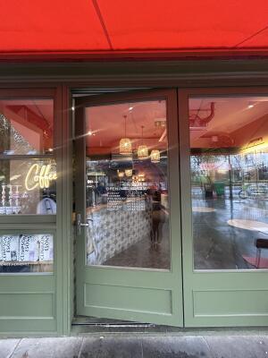 Glass door with green frames ahead. Push handle from left to open.