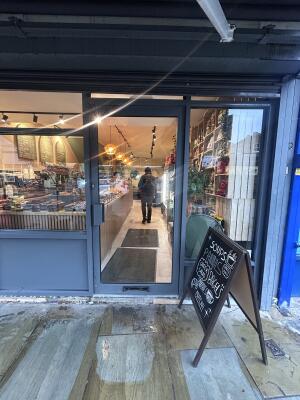 Glass door with grey metal frames ahead. Push handle on left to open. Signboard on right.