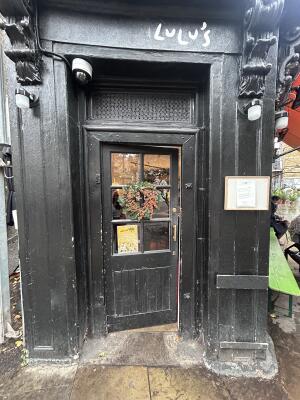 Glass door with black wooden frames ahead. Push handle on right to open.