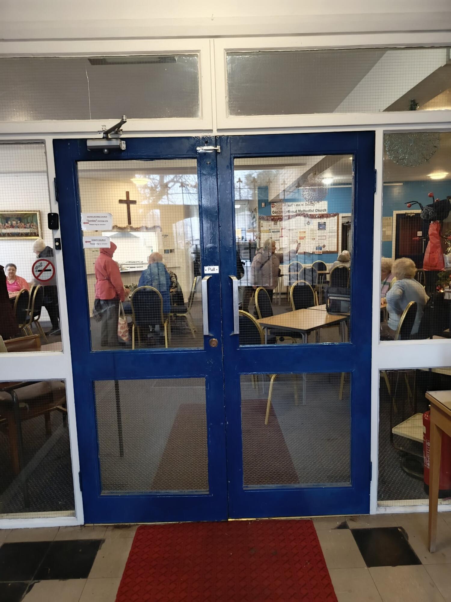From entrance facing straight. Glass door with blue frame ahead. Pull from handle at centre to open.