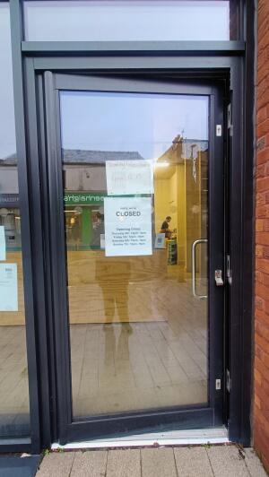Black framed glass door to venue. Push handle on right to open.