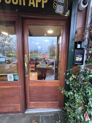 Glass door with brown wooden frames ahead. Push handle on left to open.
