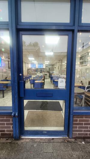 Blue panelled glass door to venue. Push handle on left to open.