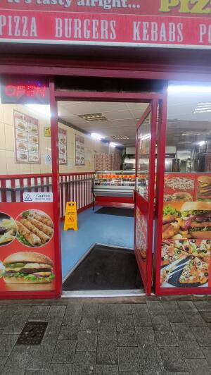 Red panelled glass door to venue. Push handle on left to open.