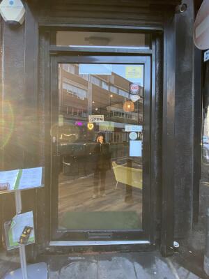 Black framed glass door. Push from left to open.